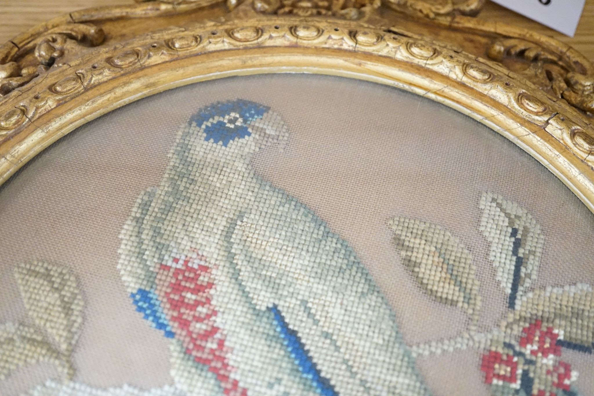 A pair of 19th century giltwood framed circular needleworks of parrots, 26cm diameter excl frame